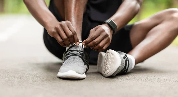 Nahaufnahme eines schwarzen Sportlers, der vor dem Training seine Schnürsenkel bindet — Stockfoto