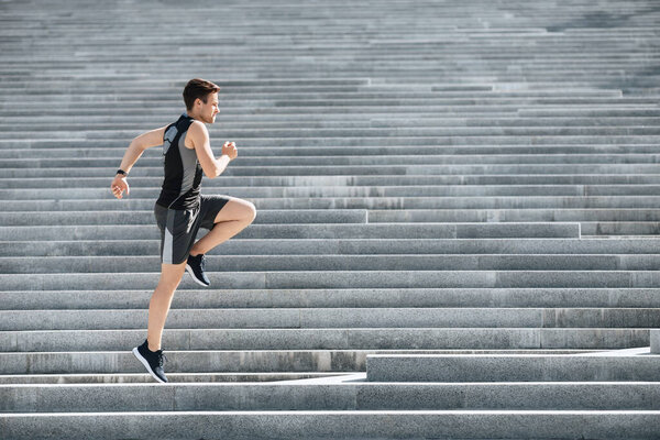 Athlete runs and jumps in morning. Man in sportswear jogging on stairs