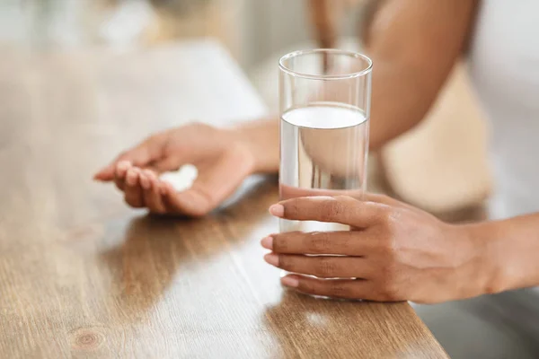 Tanımlanamayan siyah kadın evinde bir bardak suyla ilaç alıyor. — Stok fotoğraf