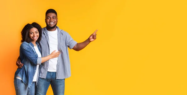 Positive Black Spouses Cuddling and Pointing At Copy Space On Yellow Background — Stock Photo, Image