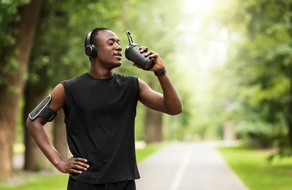 Uomo nero atletico che beve proteine mentre si allena al parco — Foto Stock