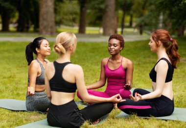 Çok uluslu güzel bayanlar nefes alma egzersizleri yapıyor ya da yoga dersinde meditasyon yapıyor.