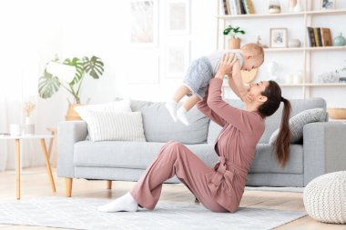 Koşulsuz Aşk. Mutlu genç anne, yeni yürümeye başlayan oğluyla eğleniyor.