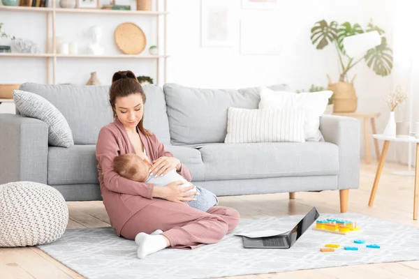 Evde laptop ve ödemelerle çalışırken bebeğe bakmak. — Stok fotoğraf