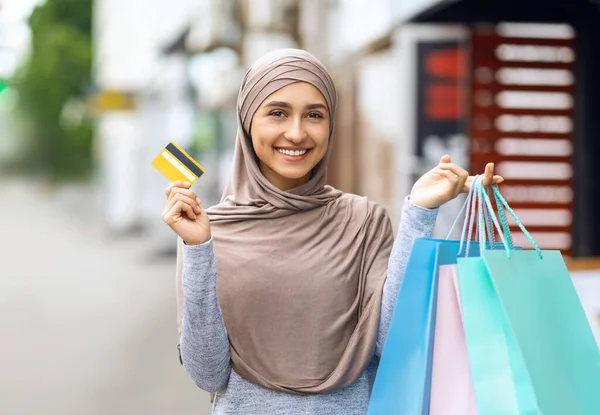 Alışveriş torbaları ve kredi kartı olan pozitif Arap kadın. — Stok fotoğraf