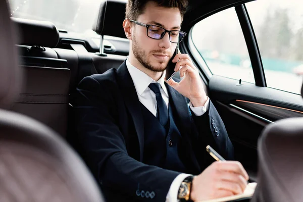 Geschäftsmann schreibt in Notizbuch im Auto — Stockfoto