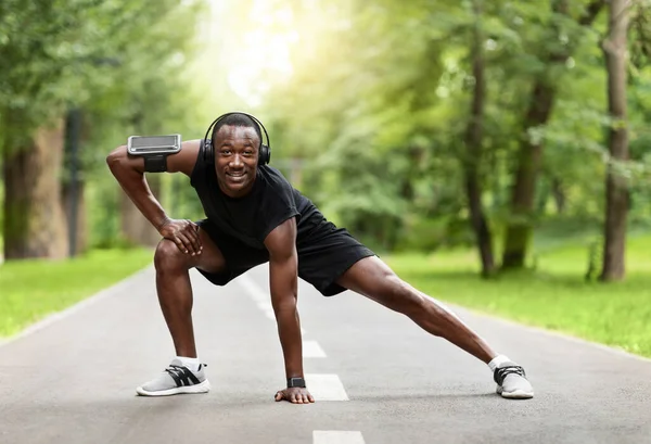 Sportlicher Schwarzer dehnt Körper vor dem Training im Park — Stockfoto