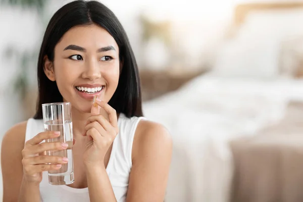 快乐的亚洲女人，服用药丸，举杯喝水 — 图库照片