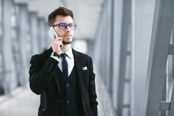 Hombre de negocios serio hablando en el teléfono inteligente con especificaciones — Foto de Stock