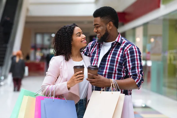 Negro amante pareja abrazando y beber café después de ir de compras juntos en el centro comercial —  Fotos de Stock