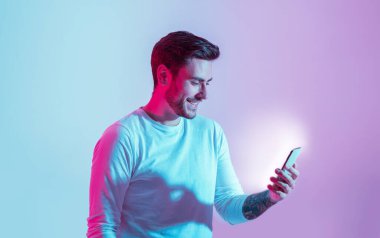 Sosyal ağdan mesajlar. Gülümseyen genç adam, parlak akıllı telefona bak.