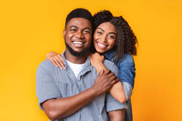 Retrato de alegre casal afro-americano posando para câmera sobre fundo amarelo — Fotografia de Stock