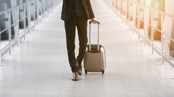 Closeup of business man walking in airport with suitcase