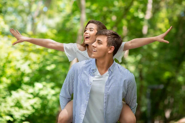 Tipo romántico dando a su novia paseo a cuestas en el hermoso parque de verano —  Fotos de Stock