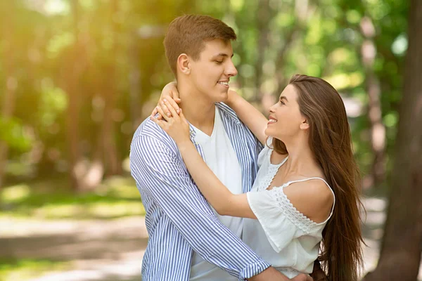 Hombre joven guapo abrazando a su encantadora esposa en el parque verde en verano, espacio vacío —  Fotos de Stock