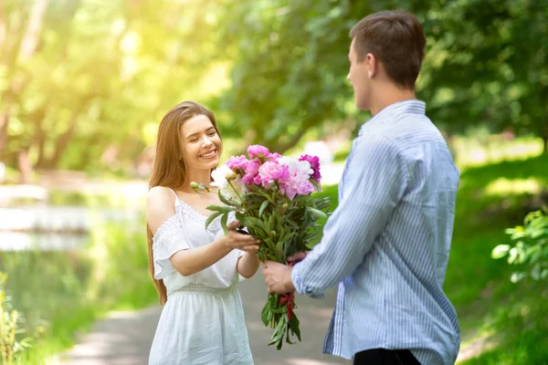 記念日だ。若いです夫驚きます彼の妻とともに花花束屋外 — ストック写真