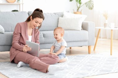 Bebekler ve Teknoloji. Dijital tabletli anne bebeğe bir şey gösteriyor.