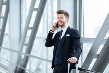 Şehir iş adamı havaalanında akıllı telefondan konuşuyor.