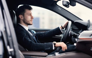 Genç iş adamı yeni arabasıyla tek başına araba kullanıyor.