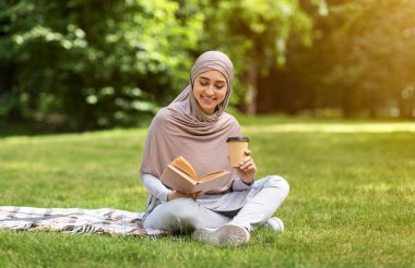 Güzel Arap kız parkta kitap okuyor.