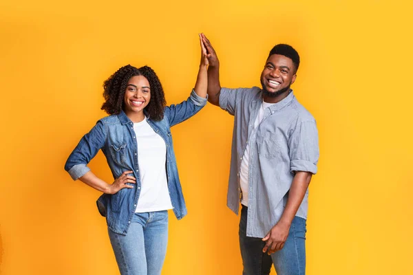 Trabalho de Equipe em Relacionamento. alegre casal preto high-fiving uns aos outros sobre fundo amarelo — Fotografia de Stock