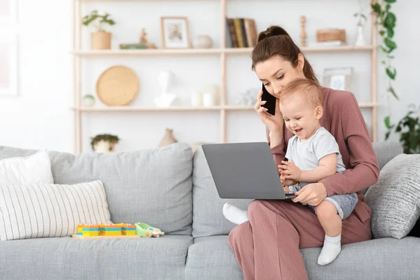 Балансировка работы и материнства. Женщина с мобильным телефоном и ноутбуком в руках ребенка — стоковое фото