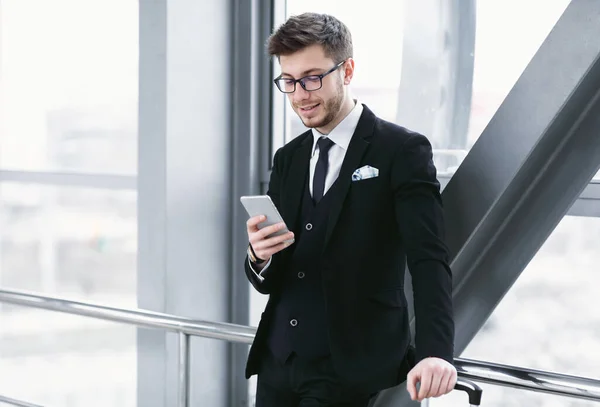 Uomo d'affari felice sms su smart phone in aeroporto — Foto Stock