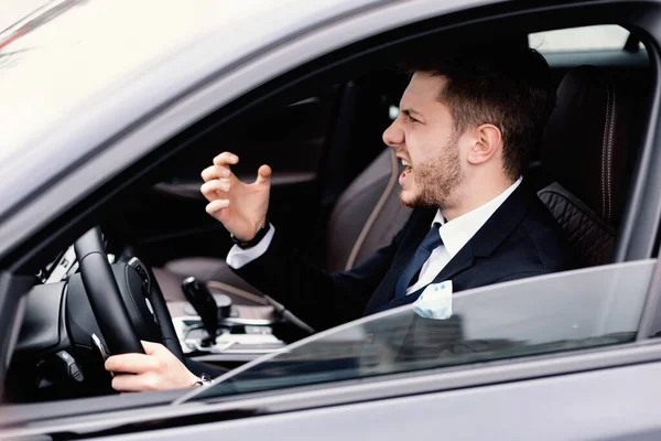 Verrückter junger Geschäftsmann fährt allein in seinem neuen Auto — Stockfoto