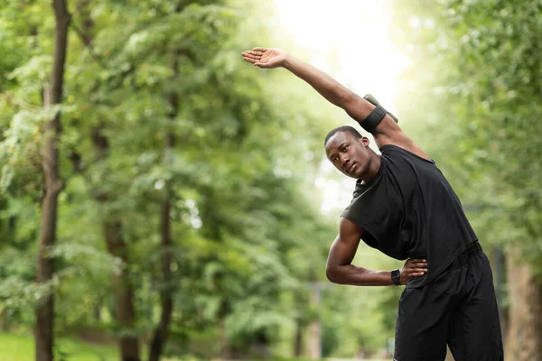 Preto cara esticando seu corpo, fazendo esporte ao ar livre — Fotografia de Stock