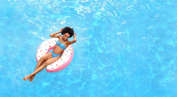 Ragazza nera rilassata galleggiante su anello gonfiabile in piscina, sopra la vista. Copia spazio — Foto Stock