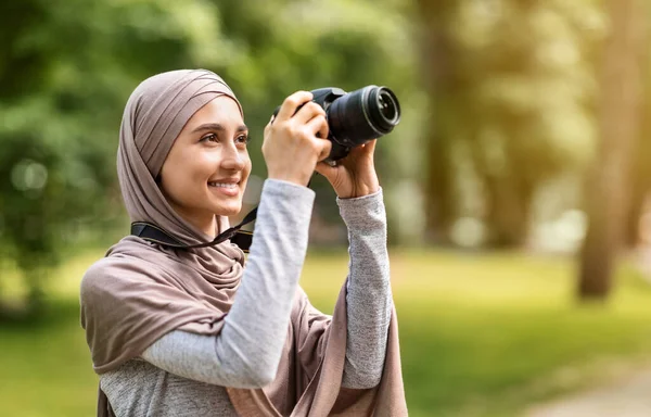 Gadis dalam jilbab mengambil foto dengan kamera profesional di taman — Stok Foto