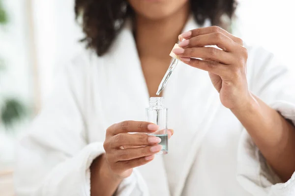 Voordelen van essentiële oliën. Fles met biologisch serum in handen van zwarte vrouw — Stockfoto