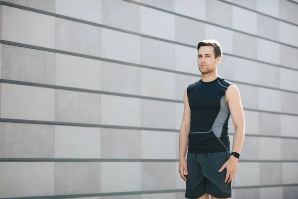 Fitness, workout, sport lifestyle. Handsome young man in sportswear with fitness tracker stands — Stock Photo, Image