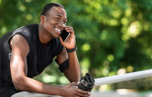 Emocionado chico africano hablando por teléfono durante el descanso, haciendo ejercicio al aire libre —  Fotos de Stock