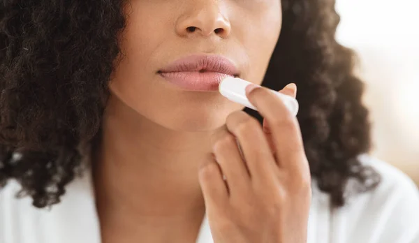 Remedios de labios agrietados. Primer plano de la mujer negra aplicando bálsamo labial hidratante Chapstick —  Fotos de Stock