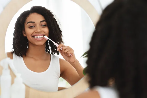 Higiene dental. Mujer sonriente limpiando dientes con cepillo de dientes cerca del espejo en casa —  Fotos de Stock