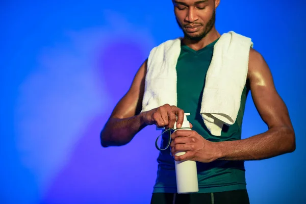 Sportsman após o exercício que abre a garrafa da água que está no estúdio — Fotografia de Stock