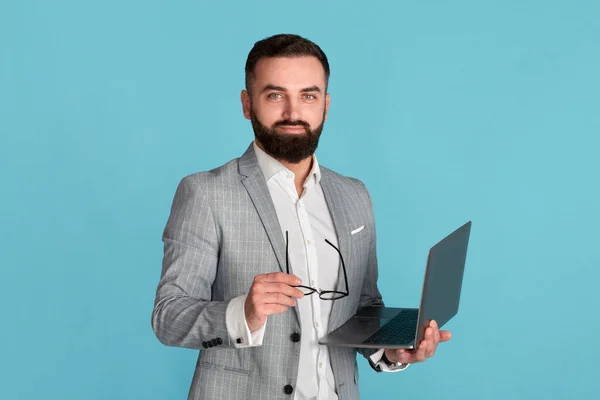 Online-Arbeit, Bildung oder Kommunikation. Selbstbewusster Firmenmitarbeiter mit Laptop auf blauem Hintergrund — Stockfoto