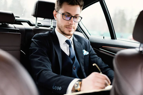 Jeune homme d'affaires signant des documents en voiture de luxe — Photo