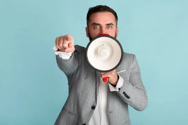 Empresário confiante em terno formal gritando em megafone sobre fundo azul — Fotografia de Stock