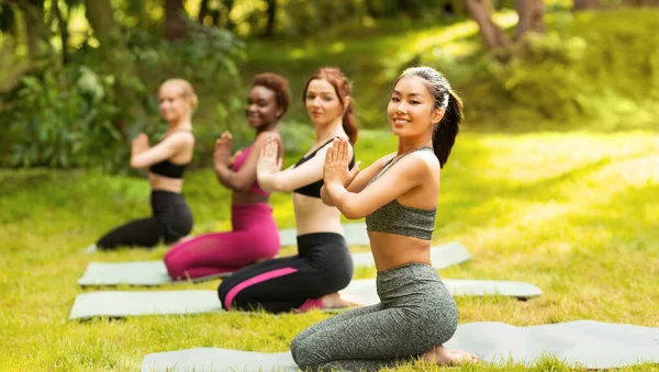 Yoga para la paz mental. Mujeres multiraciales meditando durante su práctica matutina en el parque, espacio para copiar — Foto de Stock