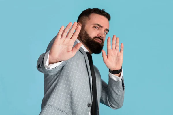 Portrait of millennial businessman refusing something, showing STOP gesture on blue background — Stock Photo, Image