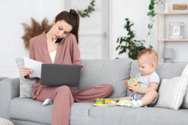 Anne bebeğe bakarken evde uzaktan çalışmakla meşgul.