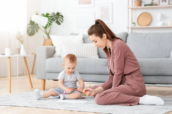 Schattige baby en zijn moeder tekenen met potloden thuis — Stockfoto