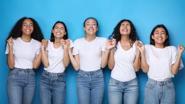 Diverses femmes faisant vœu tenant la main sur fond bleu studio — Photo