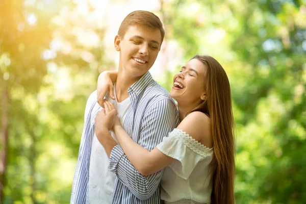 Chica joven encantadora riendo y abrazando a su novio guapo en el parque de verano —  Fotos de Stock
