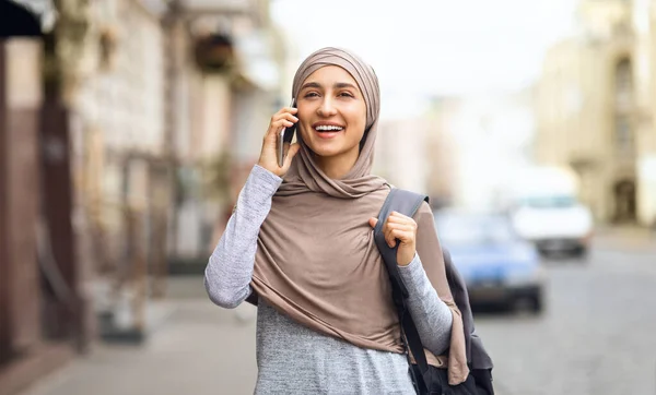 Chica en hijab hablando por teléfono mientras camina por la ciudad — Foto de Stock