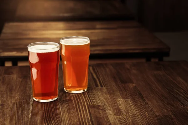 Cerveja artesanal fresca. Dois copos de bebida com espuma na mesa de madeira no interior — Fotografia de Stock