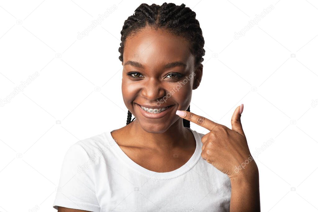 Girl Pointing Finger At Teeth With Braces Posing In Studio