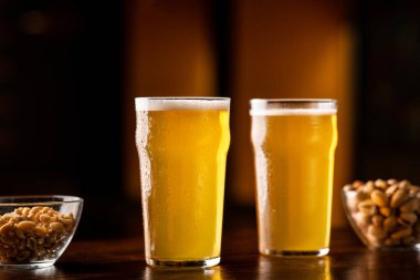 Barda bira var. İki bardak bira, fındık ve şam fıstığı.